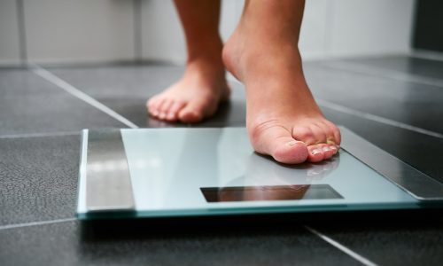 Female bare feet with weight scale in the bathroom
